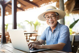 Fototapeta  - senior Asian man working remotely on laptop on summer vacation - happiness digital nomad remote work business lifestyle concept