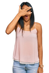 Wall Mural - Young african american woman wearing casual clothes and glasses peeking in shock covering face and eyes with hand, looking through fingers with embarrassed expression.