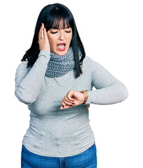 Sticker - Young hispanic plus size woman wearing winter scarf looking at the watch time worried, afraid of getting late