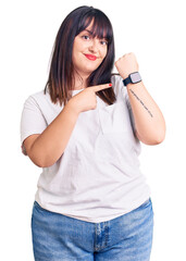 Canvas Print - Young plus size woman wearing casual clothes in hurry pointing to watch time, impatience, looking at the camera with relaxed expression