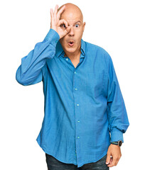 Wall Mural - Middle age bald man wearing casual clothes doing ok gesture shocked with surprised face, eye looking through fingers. unbelieving expression.