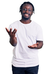 Poster - Young african american man with braids wearing casual white tshirt smiling cheerful with open arms as friendly welcome, positive and confident greetings