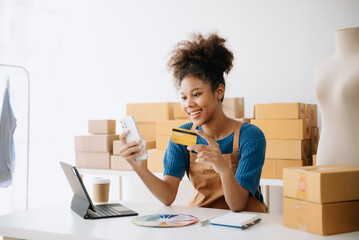 Wall Mural - Young woman holding a smartphone, tablet showing payment success and credit card with yellow parcel box as online shopping concept