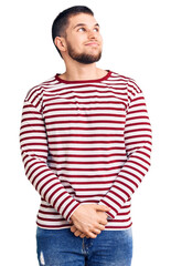 Wall Mural - Young handsome man wearing striped sweater smiling looking to the side and staring away thinking.