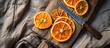 Dried orange slices and knife on wooden board from above on tablecloth