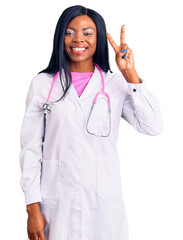 Canvas Print - Young african american woman wearing doctor stethoscope showing and pointing up with fingers number two while smiling confident and happy.