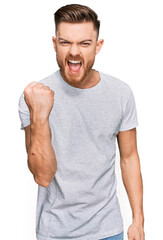 Wall Mural - Young redhead man wearing casual grey t shirt angry and mad raising fist frustrated and furious while shouting with anger. rage and aggressive concept.