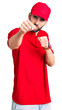 © Krakenimages.com - Young handsome man with beard wearing delivery uniform punching fist to fight, aggressive and angry attack, threat and violence