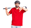 © Krakenimages.com - Young handsome man with beard playing golf holding club and ball with angry face, negative sign showing dislike with thumbs down, rejection concept