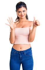 Wall Mural - Young beautiful woman wearing casual clothes showing and pointing up with fingers number six while smiling confident and happy.