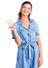 Canvas Print - Young beautiful woman wearing casual clothes smiling with happy face winking at the camera doing victory sign. number two.