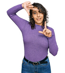 Wall Mural - Young hispanic woman wearing casual clothes smiling making frame with hands and fingers with happy face. creativity and photography concept.