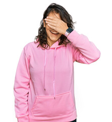 Wall Mural - Young hispanic woman wearing casual sweatshirt smiling and laughing with hand on face covering eyes for surprise. blind concept.