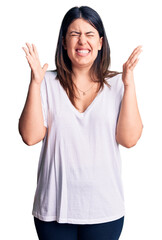 Wall Mural - Young beautiful brunette woman wearing casual t-shirt celebrating mad and crazy for success with arms raised and closed eyes screaming excited. winner concept