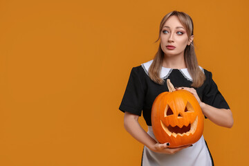 Canvas Print - Woman in scary maid costume with carved pumpkin on orange background, space for text. Halloween celebration