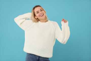 Canvas Print - Happy woman in stylish warm sweater on light blue background