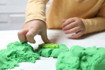 Poster - Little child playing with kinetic sand at white table, closeup