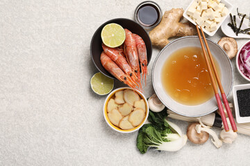 Cooking delicious ramen soup. Different ingredients and chopsticks on beige table, flat lay. Space for text