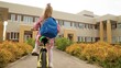 Little girl pupil with backpack riding on bike to elementary school lesson on schoolyard back view. Female kid child driving on cycle outdoor leisure sport activity transportation at campus