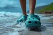 crocs shod feet of an person on the beach walking along the surf