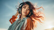 Beautiful young asian woman listening to music with headphones at sunset