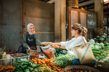 Wall Mural - greengrocery seller helping customer picking vegetables from her stall in the farmer market