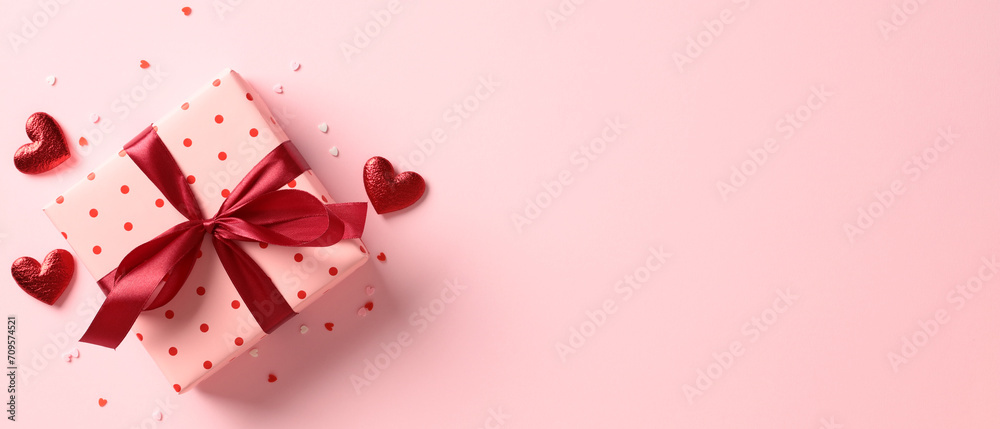Pink gift box wrapped red ribbon bow with red hearts and confetti on ...