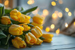 Close-up photo of bunch of yellow tulips lies on a table against the backdrop of bokeh lights. The concept of a holiday gift for a woman on World Women's Day March 8 birthday. Banner with copy space