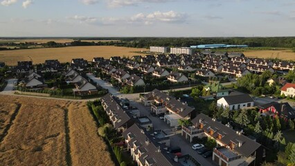 Wall Mural - Residential houses in small town near agricultural field, bird eye view. Aerial view of European suburban neighborhood with townhouses. Real estate in Poland