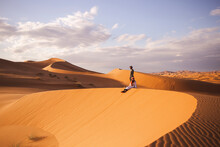 Man And Woman On Sand Dune At Sahara Desert In Morocco, Africa