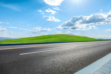 Wall Mural - Asphalt road and green meadow with mountain nature landscape under blue sky