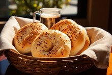  A Basket Of Bagels Sitting On Top Of A Wooden Table Next To A Glass Of Beer On Top Of A Table.