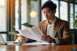 Young busy Asian business man lawyer, tax accountant manager holding paper documents checking bills, doing sales invoice accounting, reading legal contract or bank statement. Generative AI