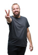© Krakenimages.com - Young caucasian hipster man over isolated background smiling with happy face winking at the camera doing victory sign. Number two.