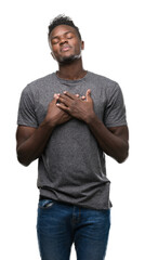 Wall Mural - Young african american man wearing grey t-shirt smiling with hands on chest with closed eyes and grateful gesture on face. Health concept.