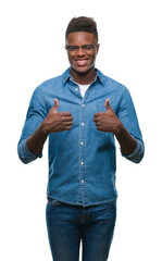 Wall Mural - Young african american man over isolated background success sign doing positive gesture with hand, thumbs up smiling and happy. Looking at the camera with cheerful expression, winner gesture.