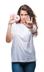 Wall Mural - Young brunette girl eating donut over isolated background with open hand doing stop sign with serious and confident expression, defense gesture