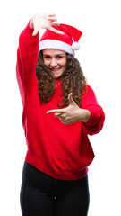 Sticker - Young brunette girl wearing christmas hat over isolated background smiling making frame with hands and fingers with happy face. Creativity and photography concept.