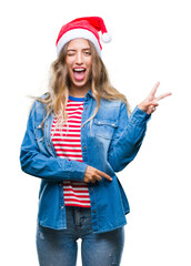 Sticker - Beautiful young blonde woman wearing christmas hat over isolated background smiling with happy face winking at the camera doing victory sign. Number two.