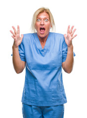 Wall Mural - Middle age blonde woman wearing doctor nurse uniform over isolated background crazy and mad shouting and yelling with aggressive expression and arms raised. Frustration concept.