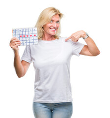 Sticker - Middle age blonde woman holding menstruation calendar ver isolated background with surprise face pointing finger to himself