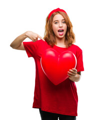 Poster - Young beautiful woman holding red heart in love over isolated background with surprise face pointing finger to himself