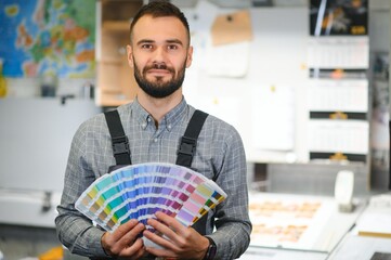 Wall Mural - Typographer standing with color swatches at the printing manufacturing