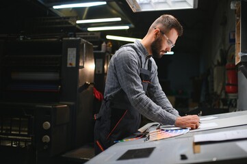 Wall Mural - Graphic engineer or worker checking imprint quality in modern print shop