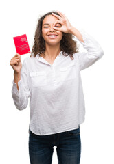 Wall Mural - Young hispanic woman holding passport of Switzerland with happy face smiling doing ok sign with hand on eye looking through fingers