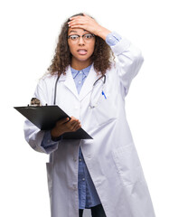 Sticker - Young hispanic doctor woman holding a clipboard stressed with hand on head, shocked with shame and surprise face, angry and frustrated. Fear and upset for mistake.