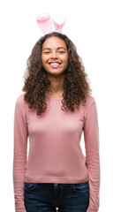 Poster - Young hispanic woman wearing easter bunny ears with a happy face standing and smiling with a confident smile showing teeth