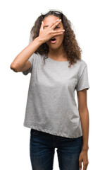 Canvas Print - Beautiful young hispanic woman wearing glasses peeking in shock covering face and eyes with hand, looking through fingers with embarrassed expression.