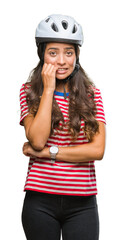 Poster - Young arab cyclist woman wearing safety helmet over isolated background looking stressed and nervous with hands on mouth biting nails. Anxiety problem.