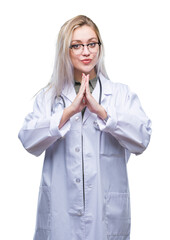 Sticker - Young blonde doctor woman over isolated background praying with hands together asking for forgiveness smiling confident.